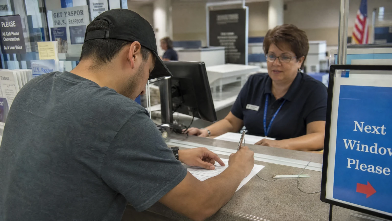 A person filling out business registration paperwork at a government counter